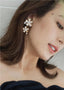 Double flower and pearl gold stud earring on model in black dress