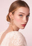Gold open flower earring with pearl centers on model in lace dress (side view)
