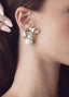 Close-up of a woman wearing a floral earring with a pearl accent.