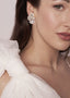 Close-up of a woman wearing pearl floral stud earrings with a soft background